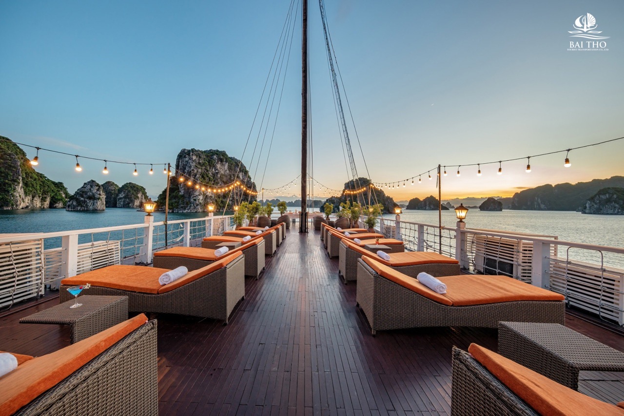 Relaxing cruise balcony with scenic Halong Bay views at sunset.