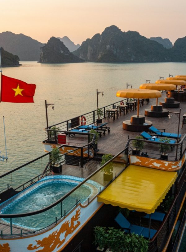 Scenic view of a luxury cruise boat with sun loungers and a hot tub on Halong Bay at sunset.