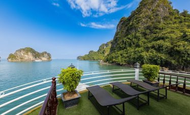 Stunning view of Halong Bay with lush green islands and calm waters from a cruise balcony.