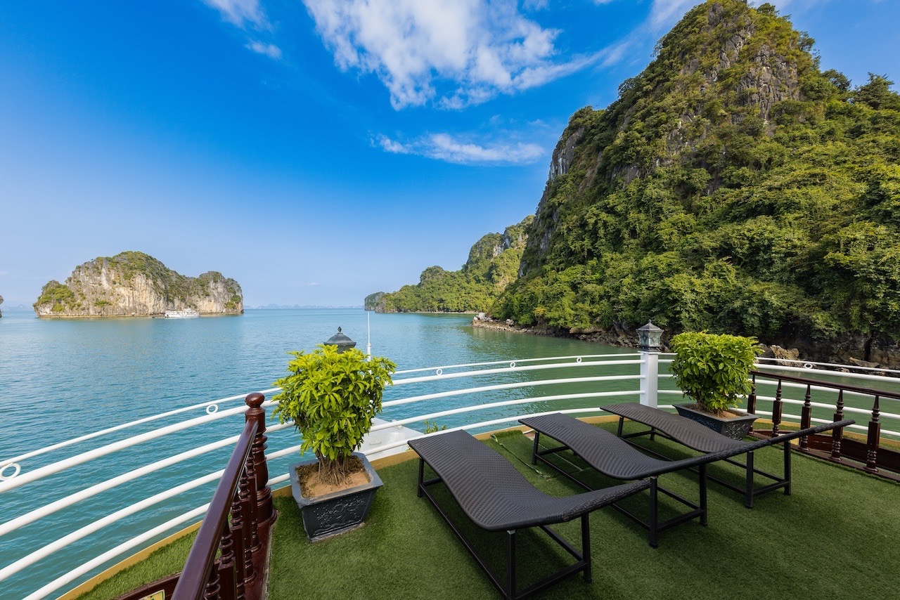 Stunning view of Halong Bay with lush green islands and calm waters from a cruise balcony.