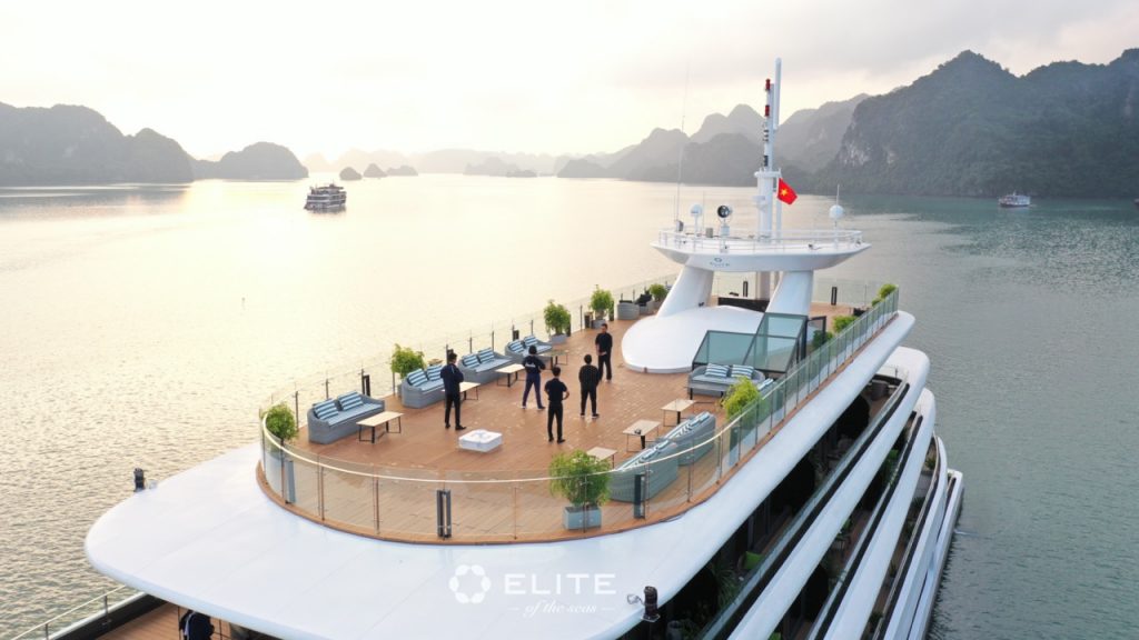 Luxury Halong Bay cruise deck with panoramic views and guests enjoying the scenery.