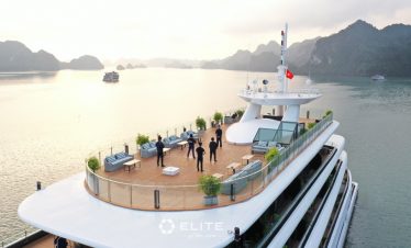 Luxury Halong Bay cruise deck with panoramic views and guests enjoying the scenery.