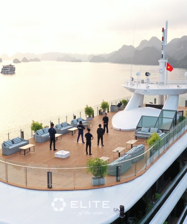 Luxury Halong Bay cruise deck with panoramic views and guests enjoying the scenery.
