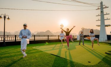 Vibrant scene of people enjoying traditional dance and music on a Halong Bay cruise at sunset.