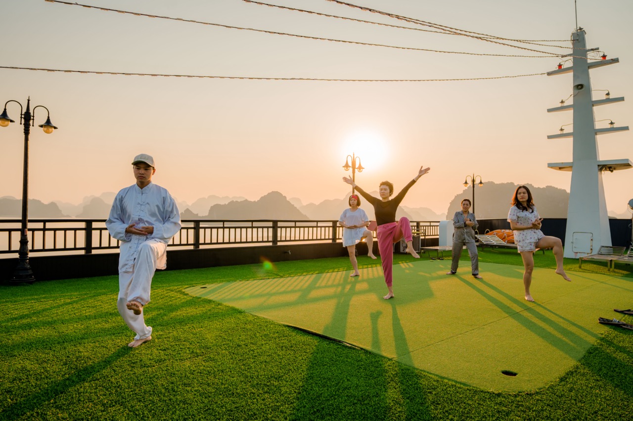Vibrant scene of people enjoying traditional dance and music on a Halong Bay cruise at sunset.