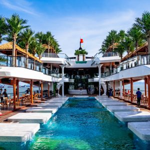 Luxurious waterfront resort with infinity pool, palm trees, and ocean views in Vietnam.