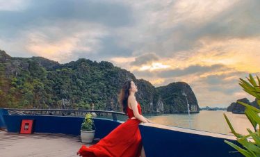 Lan Ha Bay Cruise 1 Night - Stunning Halong Bay scenery with a woman enjoying the sunset from a cruise balcony, capturing the tr.