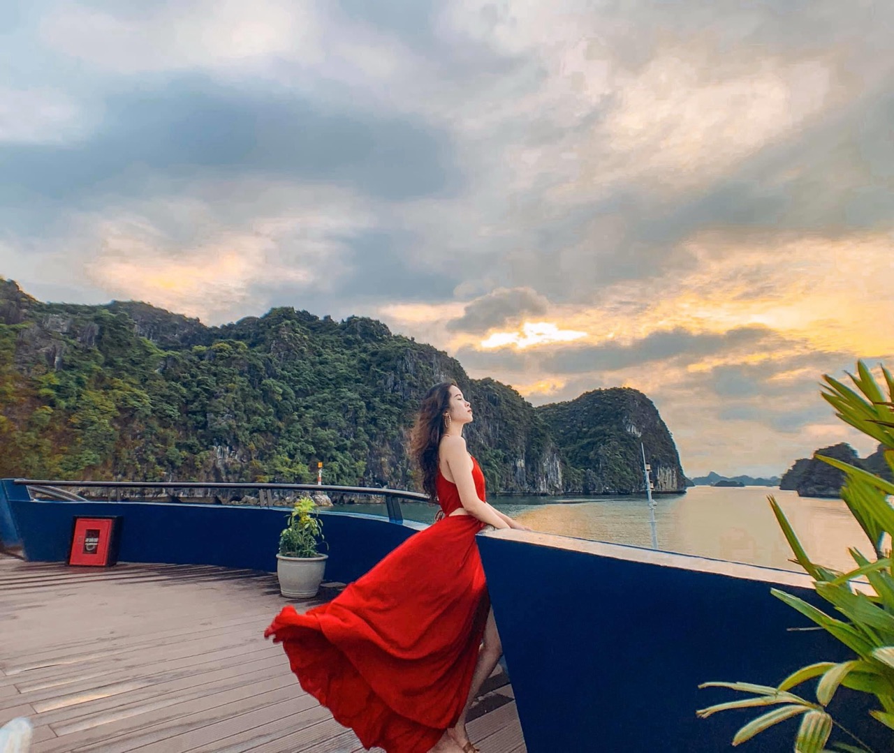 Lan Ha Bay Cruise 1 Night - Stunning Halong Bay scenery with a woman enjoying the sunset from a cruise balcony, capturing the tr.