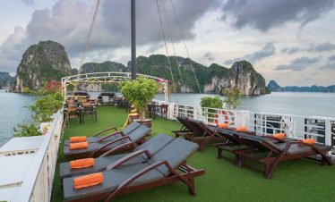 Relaxing cruise balcony with sun loungers and scenic views of Halong Bay.