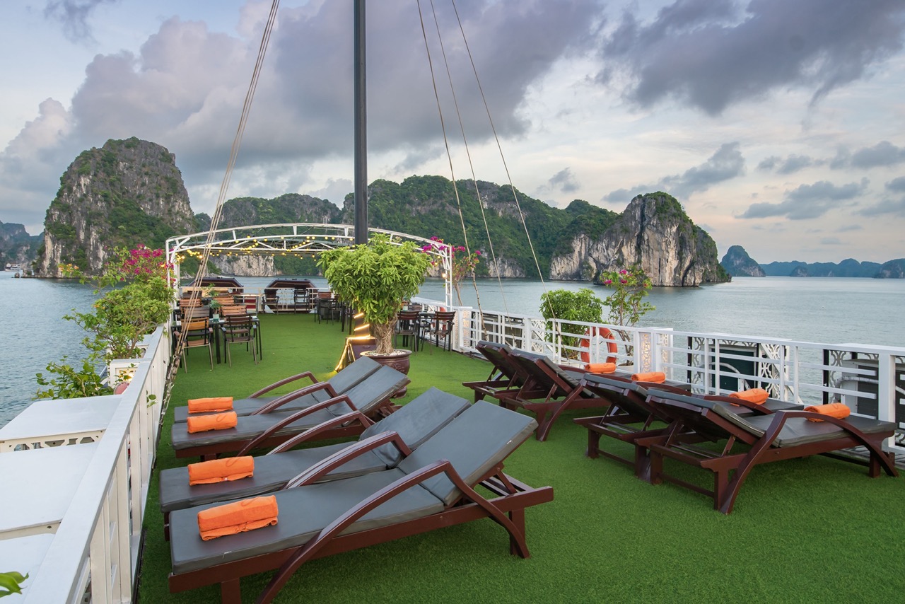 Relaxing cruise balcony with sun loungers and scenic views of Halong Bay.