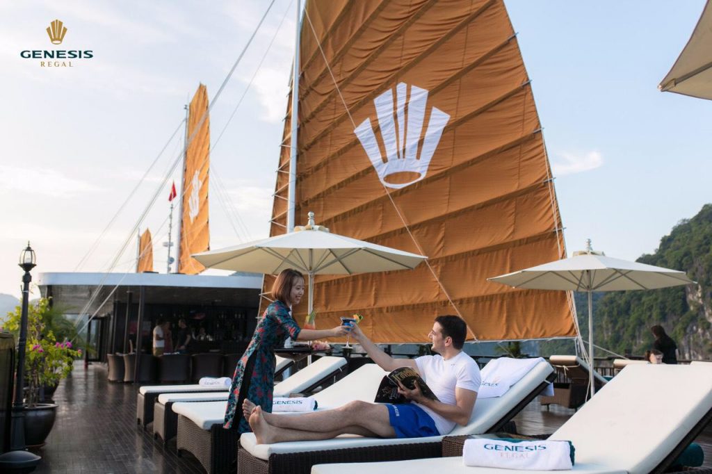 Relaxing couple enjoying a scenic Halong Bay cruise balcony with stunning views and luxurious amenit.