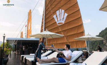 Relaxing couple enjoying a scenic Halong Bay cruise balcony with stunning views and luxurious amenit.
