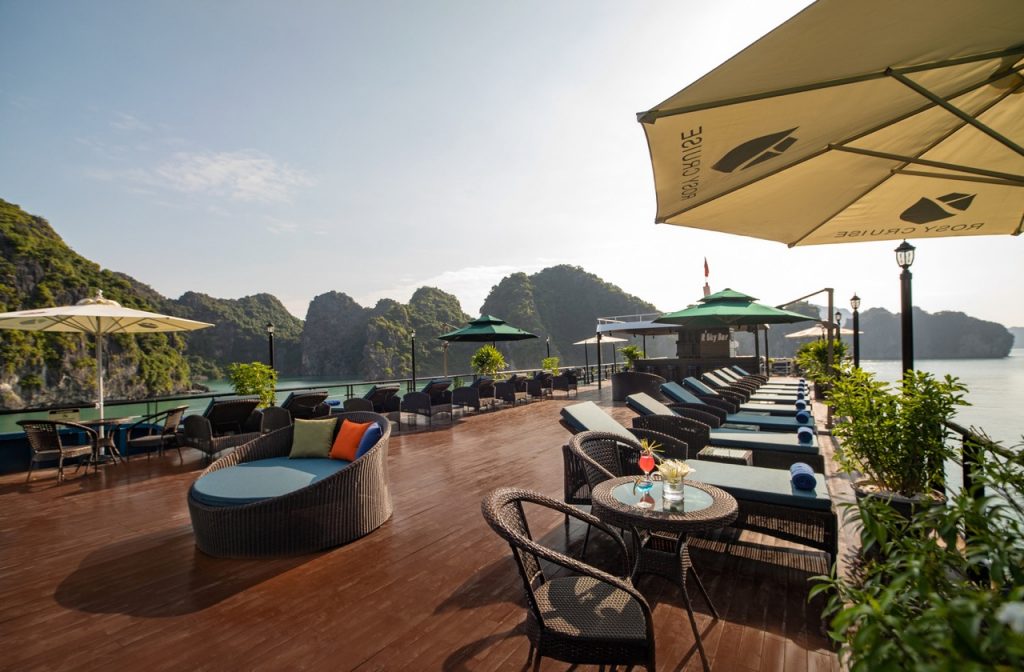 Scenic view of a cruise balcony in Halong Bay with lounge chairs and umbrellas, overlooking limeston.