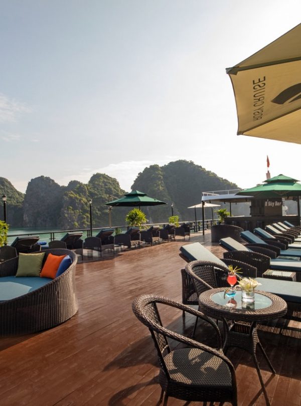 Scenic view of a cruise balcony in Halong Bay with lounge chairs and umbrellas, overlooking limeston.