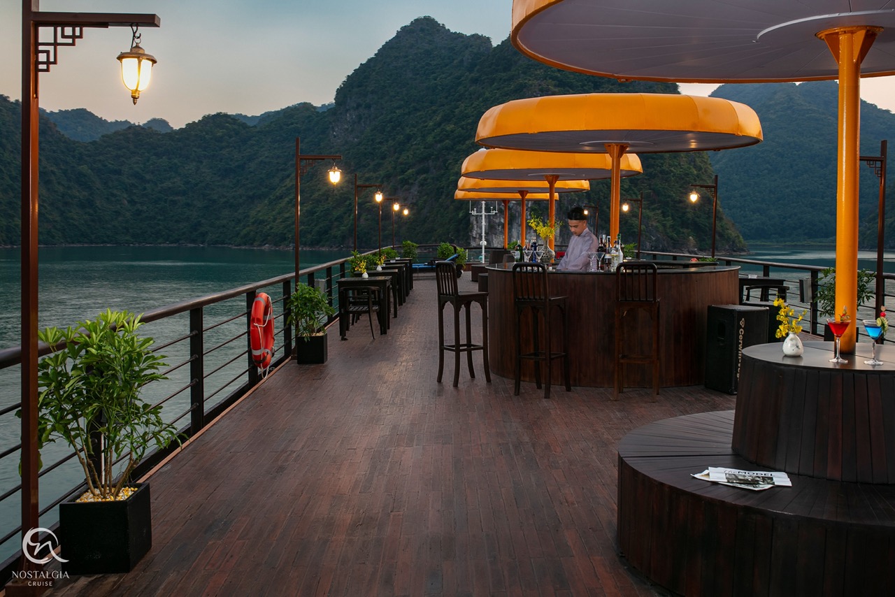 Relaxing cruise deck overlooking Halong Bay with scenic mountain views and cozy seating.