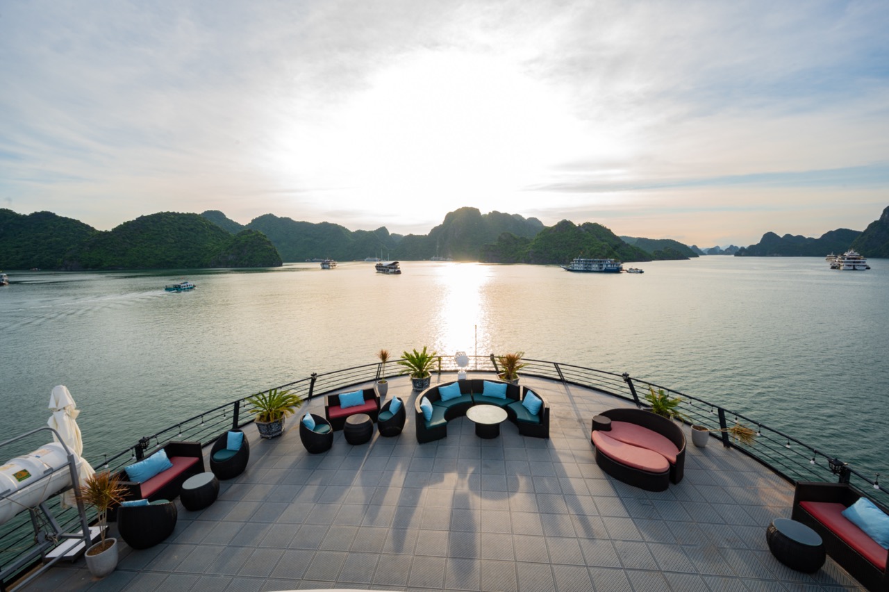 Cruise balcony view of Halong Bay with boats and scenic limestone islands at sunset.