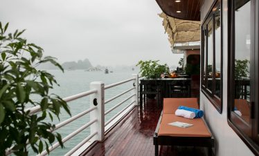 Scenic view from a luxury cruise balcony in Halong Bay with calm waters and lush islands.