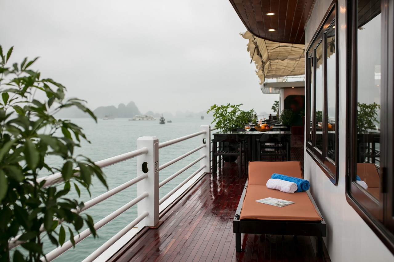 Scenic view from a luxury cruise balcony in Halong Bay with calm waters and lush islands.