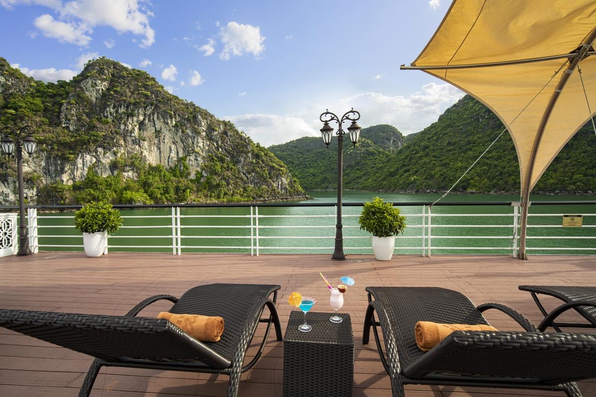 Serene lake view with outdoor lounge, sun umbrellas, and refreshing cocktails, perfect for relaxation in Vietnam.