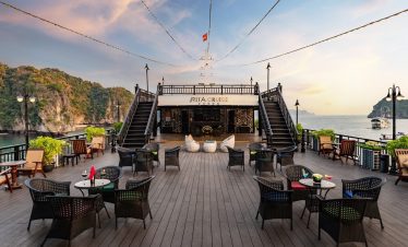 Beautiful Halong Bay cruise balcony with seating and sunset sky.