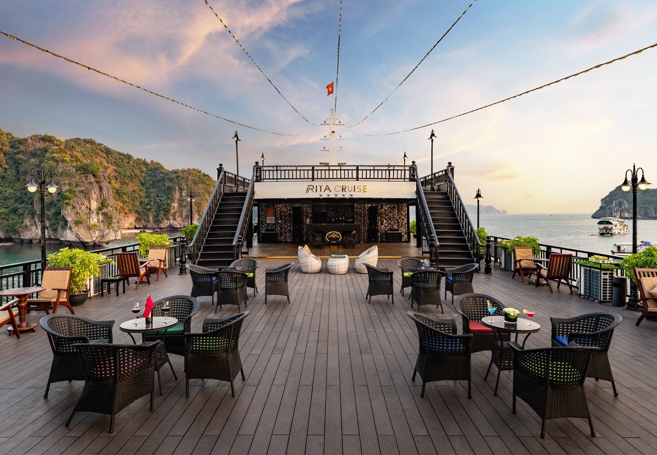 Beautiful Halong Bay cruise balcony with seating and sunset sky.