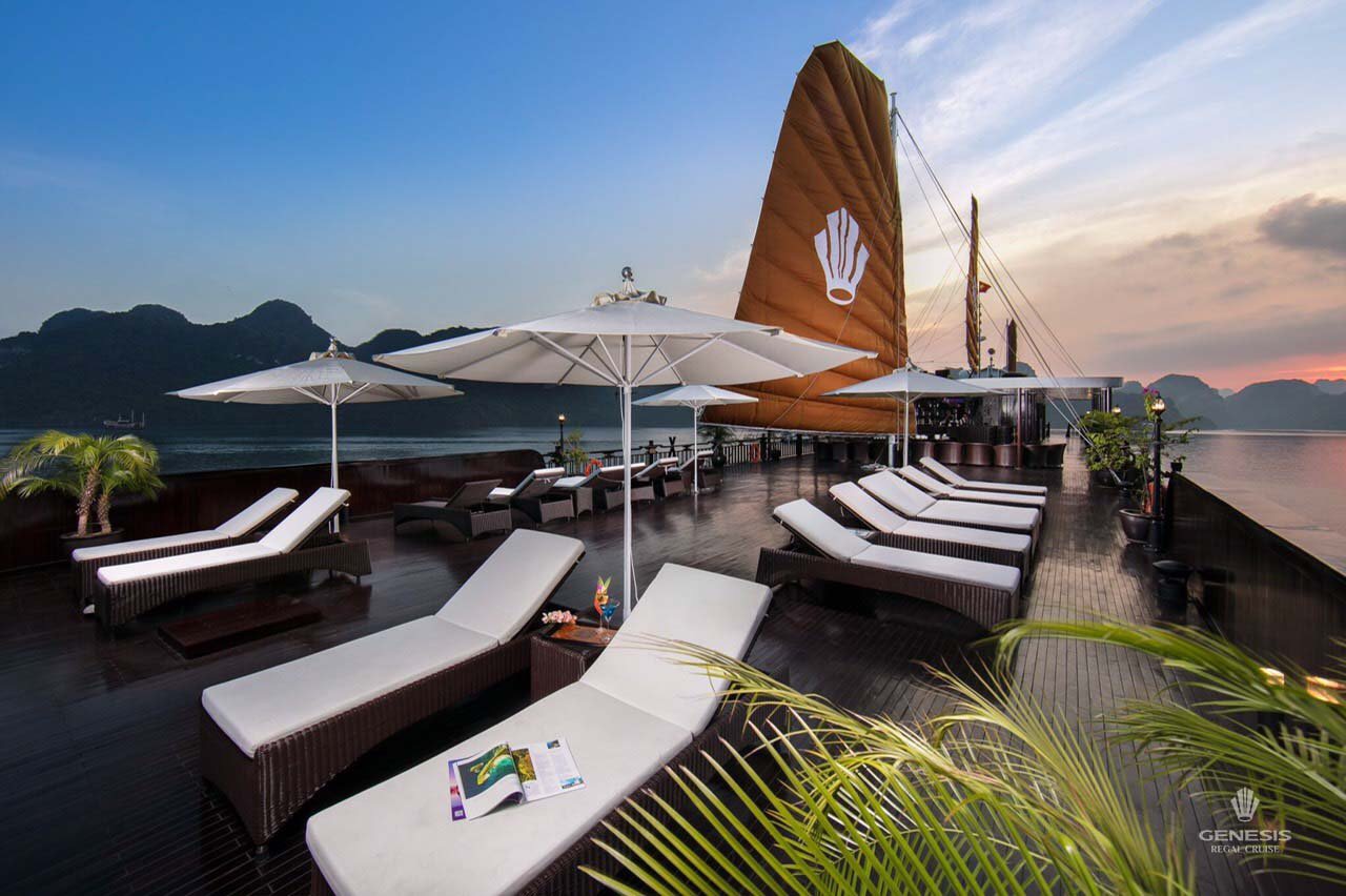 Luxurious cruise deck in Halong Bay with sun loungers, umbrellas, and scenic mountain views, perfect.