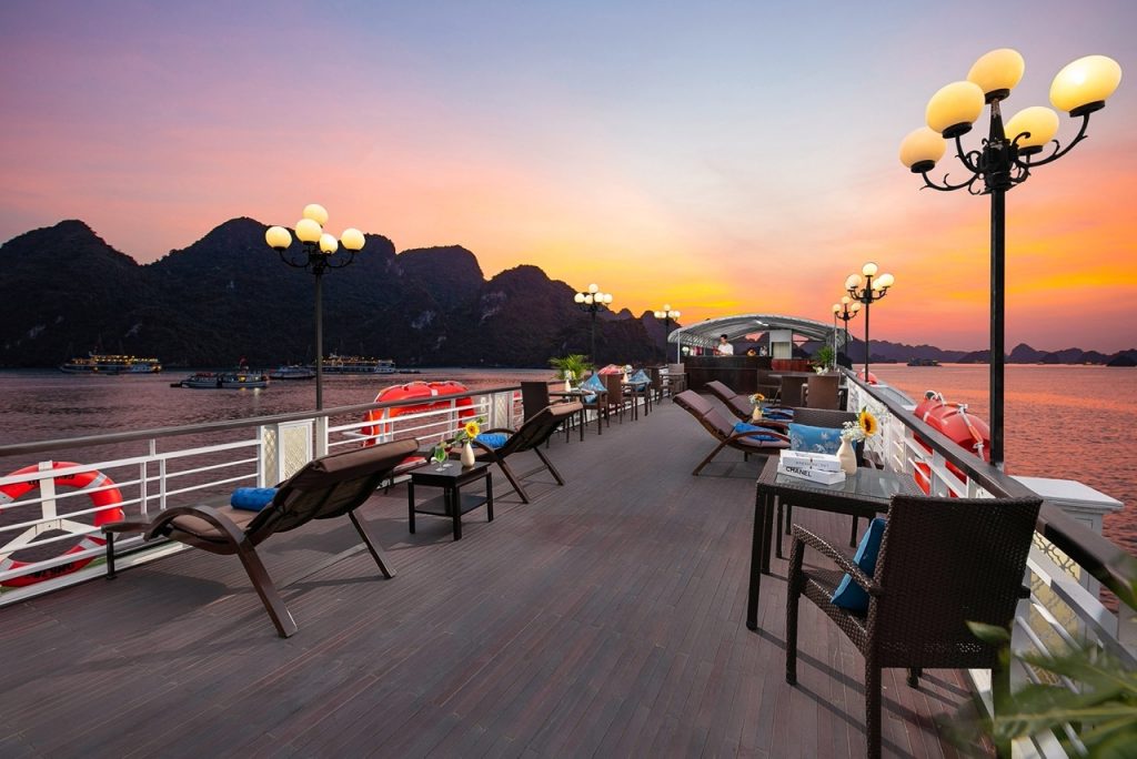 Scenic Halong Bay cruise deck with lounge chairs and sunset view, perfect for relaxing and sightseei.