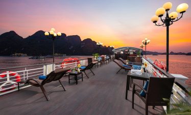 Scenic Halong Bay cruise deck with lounge chairs and sunset view, perfect for relaxing and sightseei.