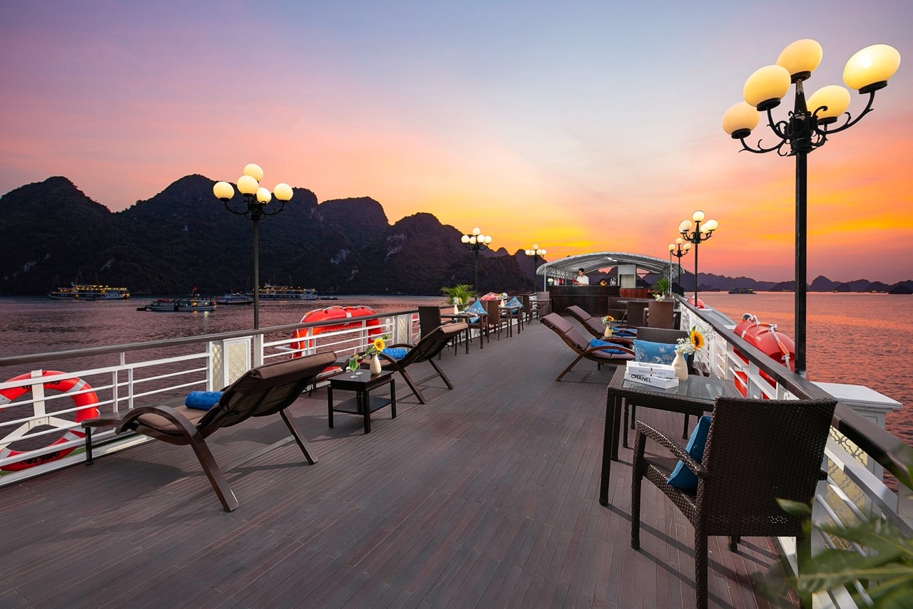 Scenic Halong Bay cruise deck with lounge chairs and sunset view, perfect for relaxing and sightseei.