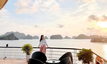 Breathtaking ocean view with woman enjoying sunset from cruise deck at Halong Bay.