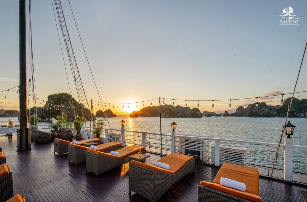 Sunset over Bai Tu Long Bay with luxurious cruise deck, comfortable seating, and tranquil waters, pe.