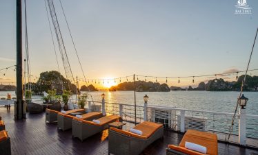Sunset over Bai Tu Long Bay with luxurious cruise deck, comfortable seating, and tranquil waters, pe.