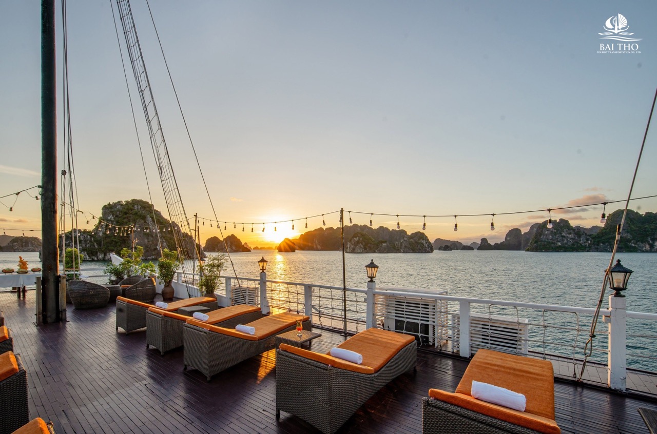Sunset over Bai Tu Long Bay with luxurious cruise deck, comfortable seating, and tranquil waters, pe.
