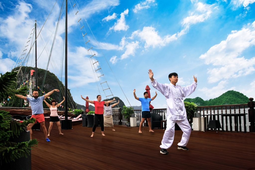Yoga session on cruise deck with scenic Halong Bay backdrop, peaceful and relaxing atmosphere.