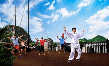 Yoga session on cruise deck with scenic Halong Bay backdrop, peaceful and relaxing atmosphere.