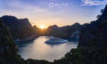 Stunning sunset over Halong Bay with luxury cruise and towering limestone karsts.