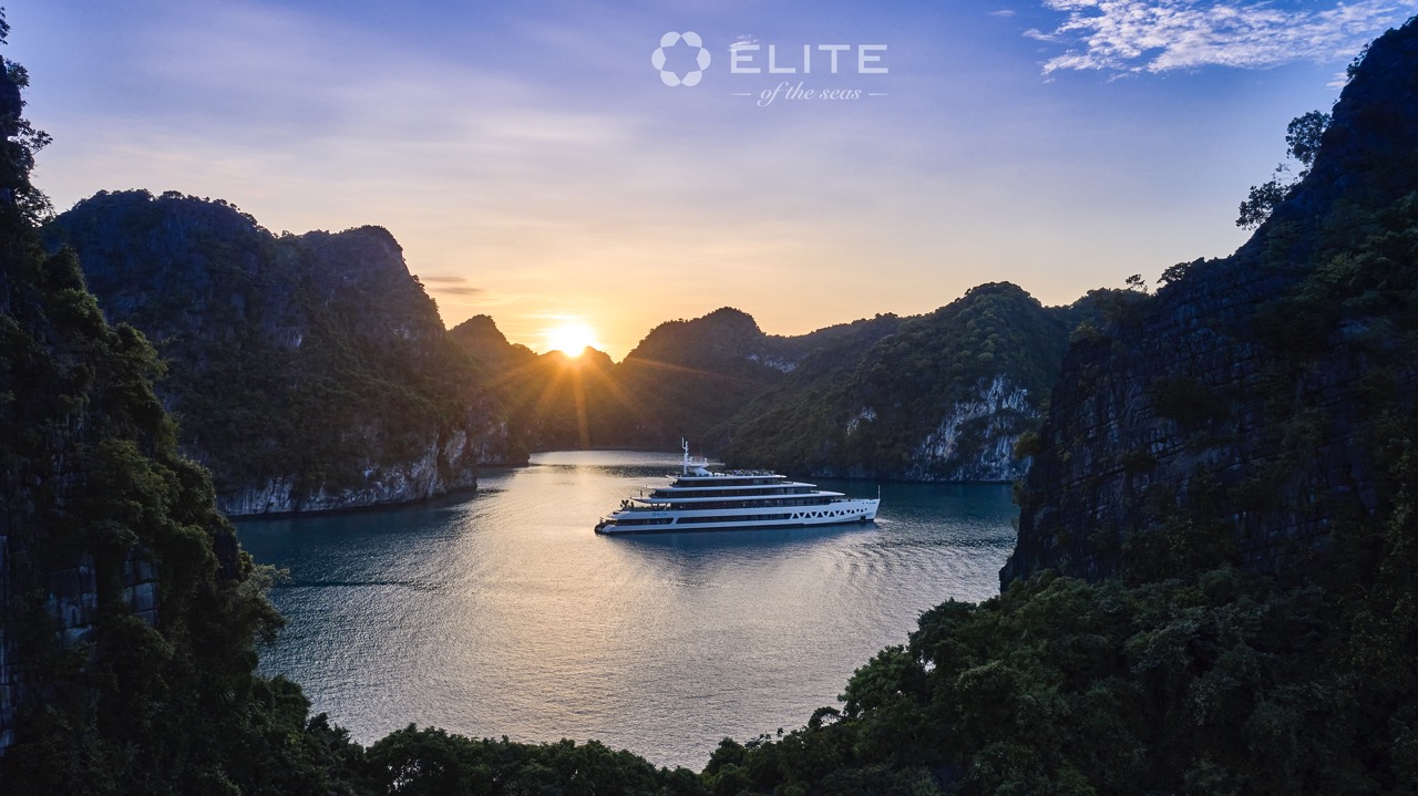 Stunning sunset over Halong Bay with luxury cruise and towering limestone karsts.