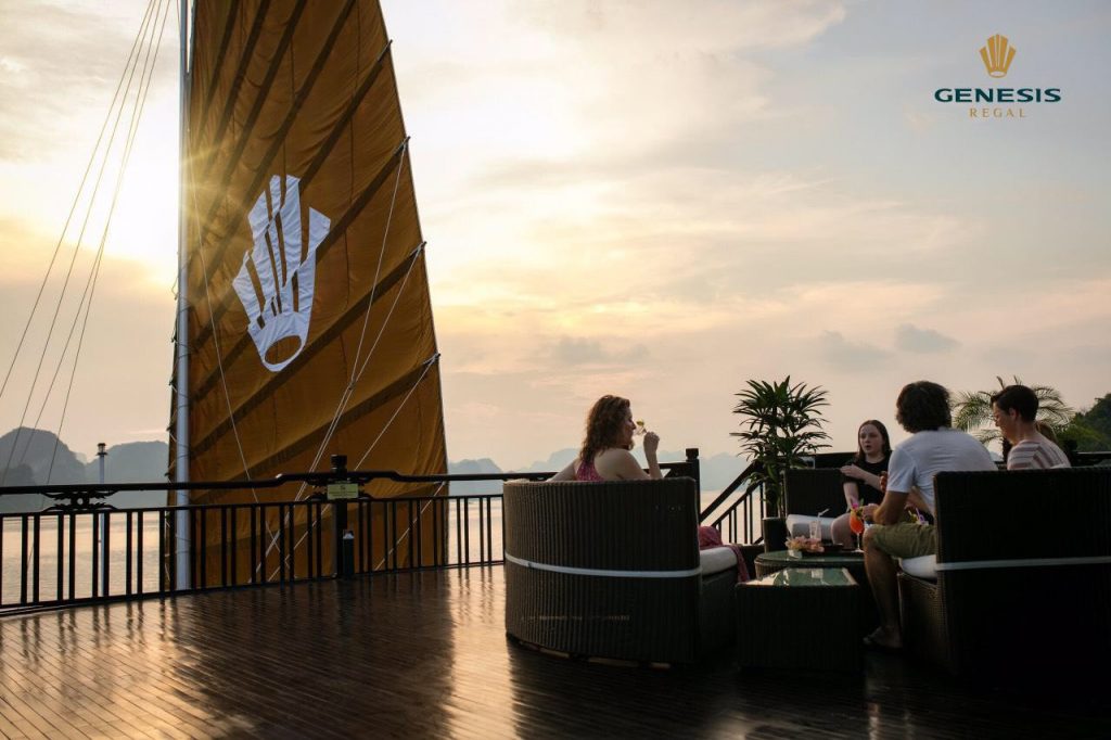 Scenic Halong Bay cruise balcony with friends enjoying sunset views and drinks, capturing the tranqu.