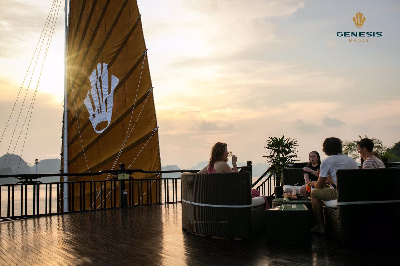 Scenic Halong Bay cruise balcony with friends enjoying sunset views and drinks, capturing the tranqu.