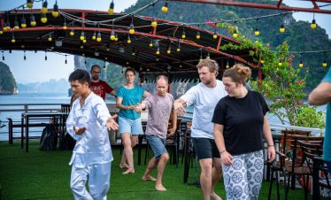 Enjoying lively outdoor party on a Halong Bay cruise deck with scenic limestone karsts in the backgr.