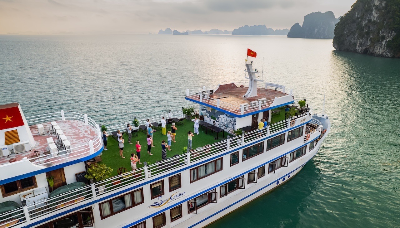 Scenic view of Swan Cruise boat in Halong Bay with passengers enjoying the outdoor deck.