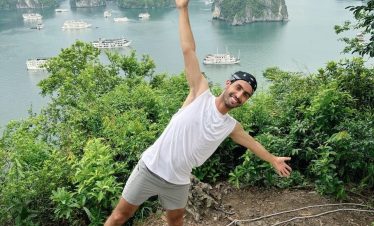Scenic view of limestone islands in Halong Bay with lush greenery and boats, perfect for trekking an.