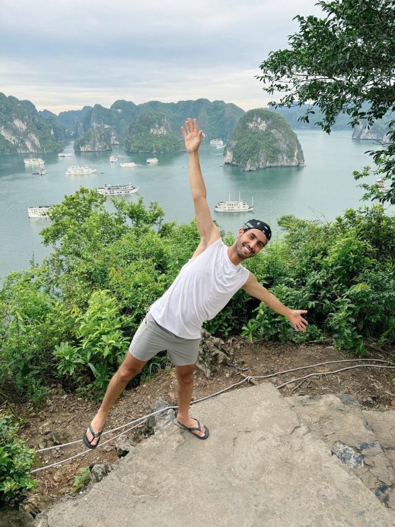 Scenic view of limestone islands in Halong Bay with lush greenery and boats, perfect for trekking an.
