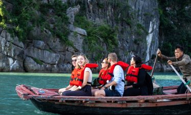 People kayaking on Bai Tu Long Bay with scenic limestone cliffs and lush greenery.