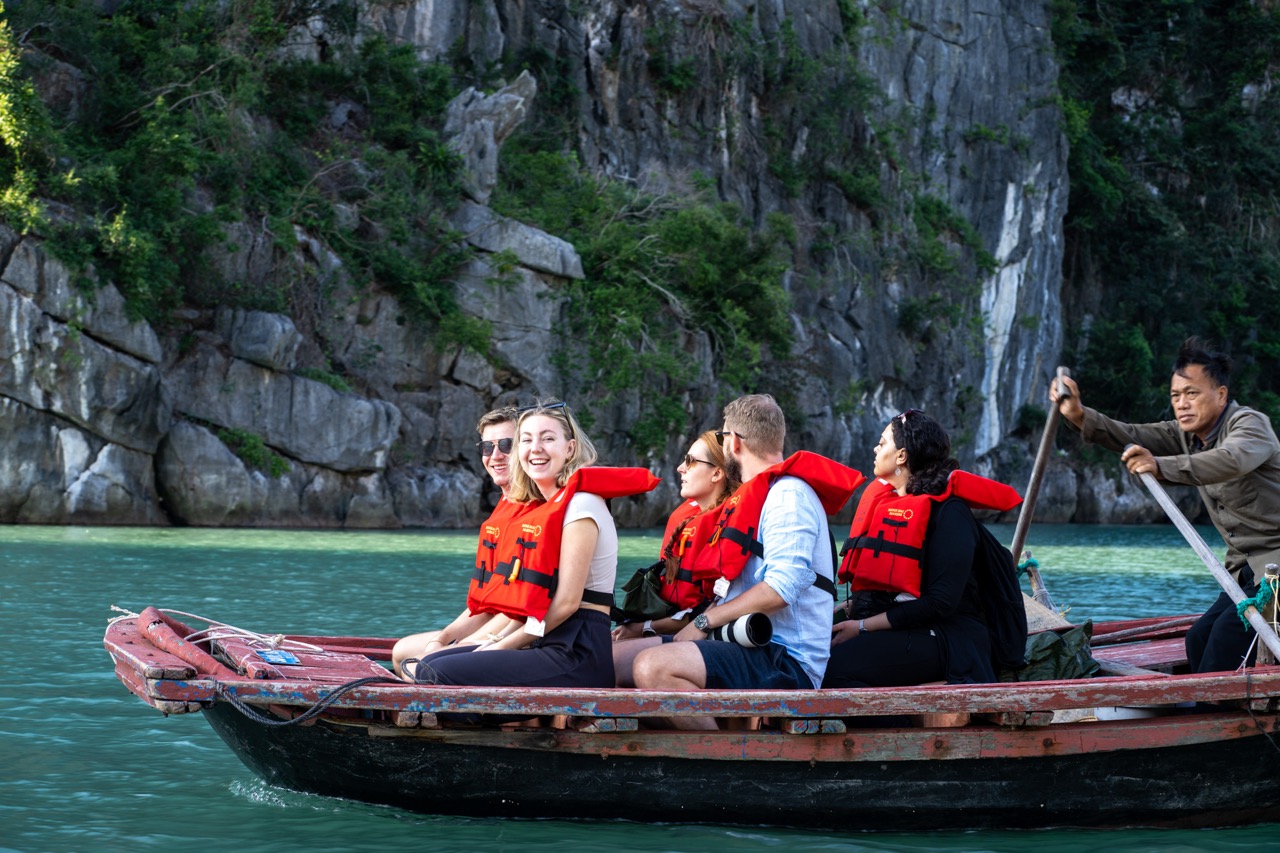 People kayaking on Bai Tu Long Bay with scenic limestone cliffs and lush greenery.