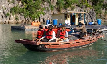 Kayaking adventure on Halong Bay cruise balcony with scenic limestone cliffs.