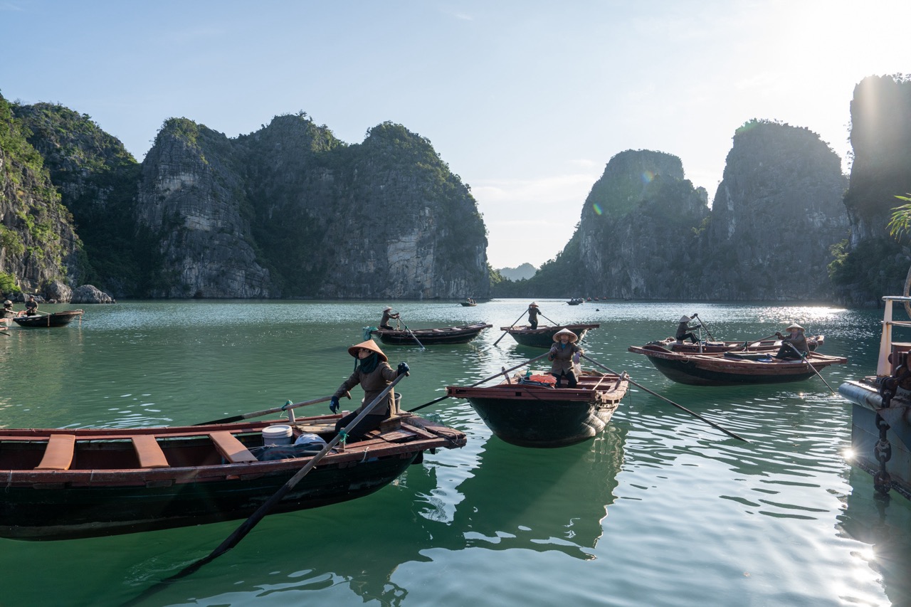 Scenic Bai Tu Long Bay with boats and limestone karsts under bright sky, perfect for cruising and ex.