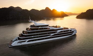 A modern luxury cruise ship sailing through Lan Ha Bay's stunning limestone karsts during sunset, pe.