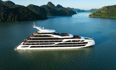 Luxury cruise ship sailing on Lan Ha Bay with scenic limestone karsts and calm waters.