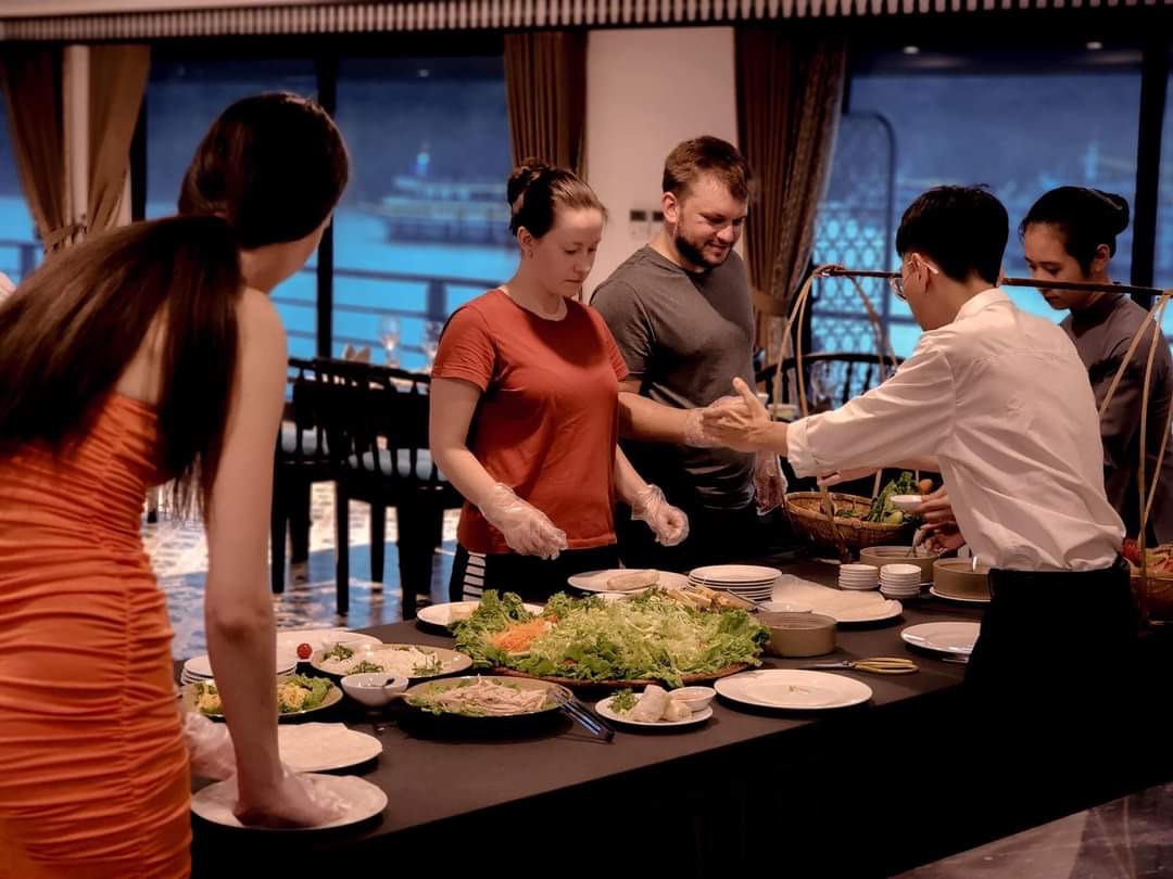 People enjoying a delicious meal on cruise in Lan Ha Bay, Vietnam, with scenic water views in the ba.